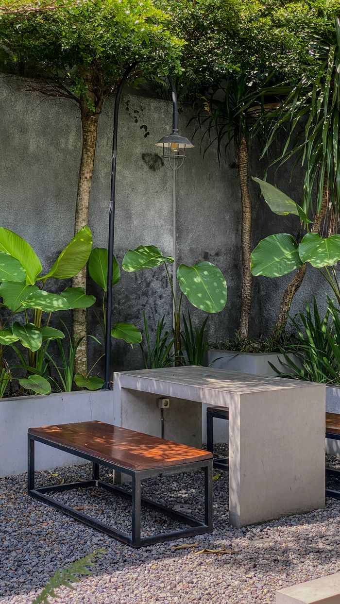 A modern concrete table and benches in a leafy outdoor garden, perfect for a tranquil escape.