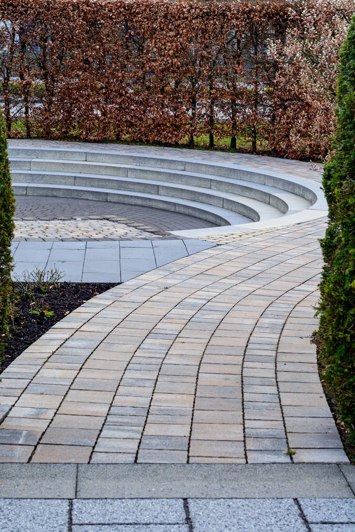Curved brick pathway leading to a sunken seating area in Coesfeld garden.